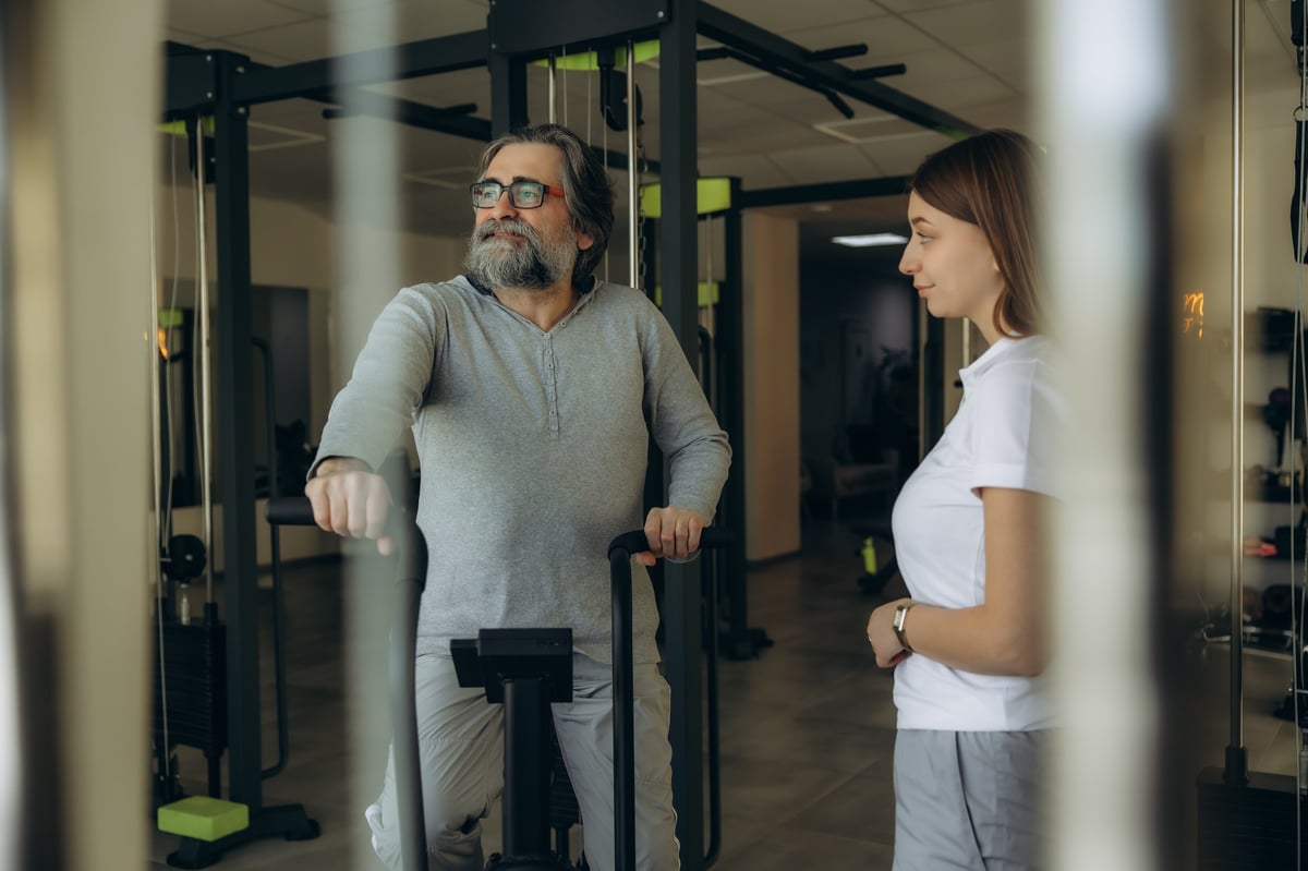 Personal trainer coaching a mature client in a bright gym